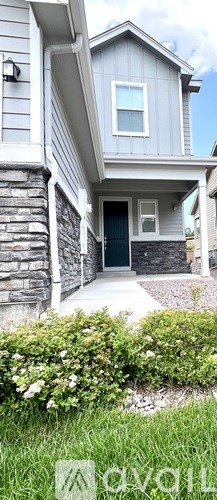 A house with a grey facade and a green lawn in front.
