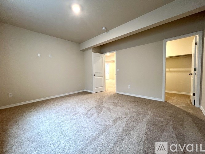 A spacious room with a carpeted floor and a doorway leading to another room.