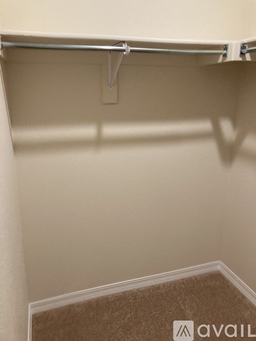 A white closet with a metal rod and a carpeted floor.