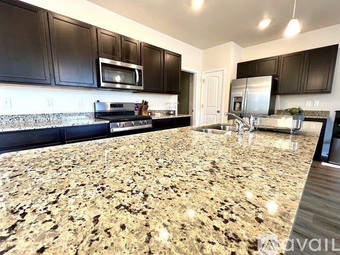 A kitchen with granite countertops and black cabinets.