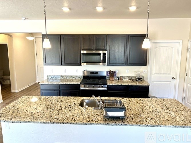 A kitchen with granite countertops and black cabinets.