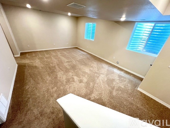 A room with a carpeted floor and a window with blinds.