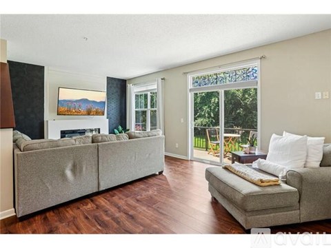 A living room with a grey couch and a painting of a mountain scene on the wall.