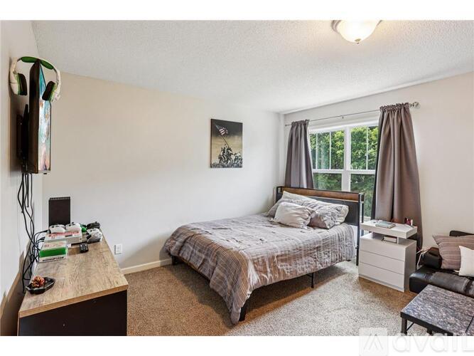 A bedroom with a bed, nightstand, and chair.