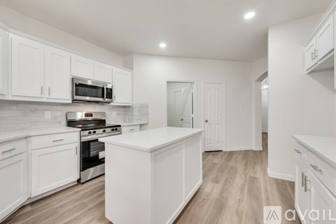 A kitchen with white cabinets and a wooden floor.