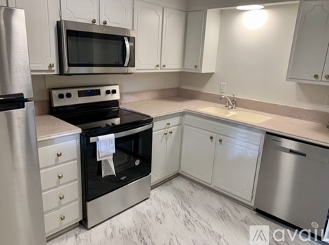 A kitchen with white cabinets and a stainless steel refrigerator.