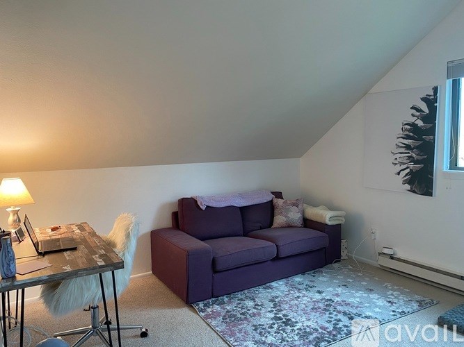 A living room with a purple couch and a wooden table.