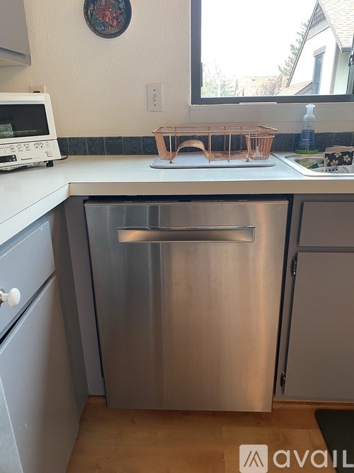 A kitchen with a stainless steel dishwasher and a white microwave.