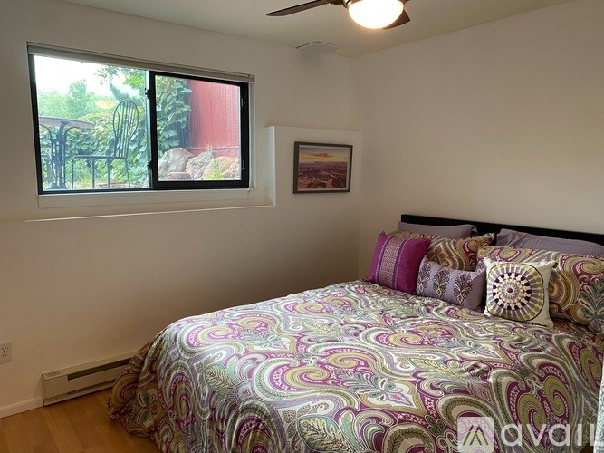 A bedroom with a bed and a window overlooking a garden.