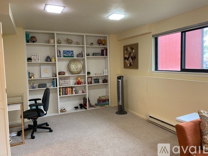A room with a desk, chair, and bookshelf filled with various items.