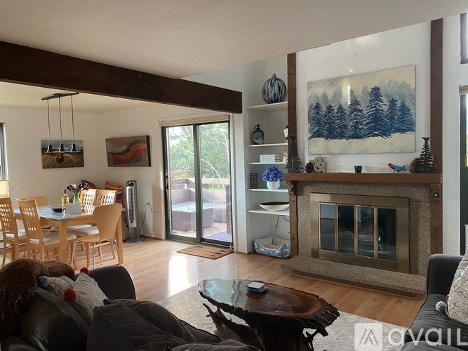A living room with a fireplace and a painting of trees on the wall.
