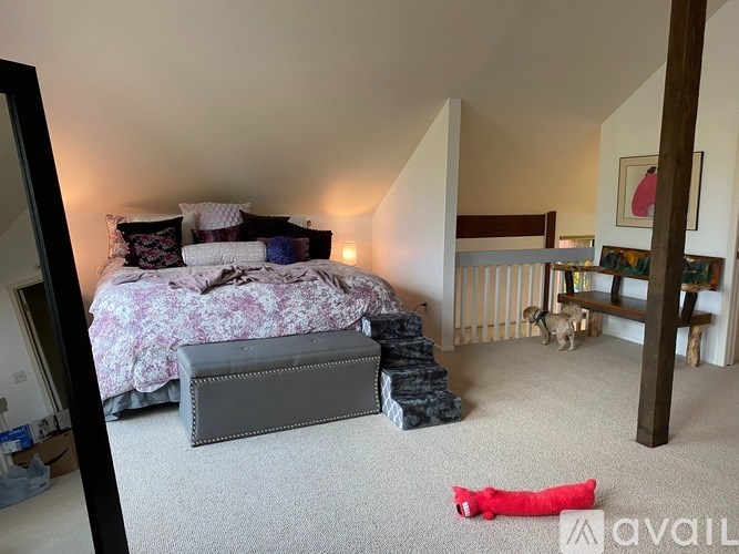 A bedroom with a bed, a dog, a bench, and a red object on the floor.