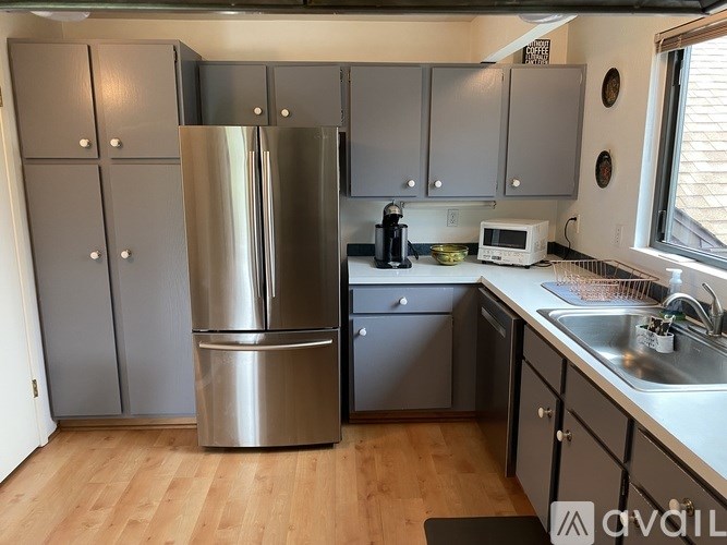 A kitchen with a stainless steel refrigerator and wooden floors.