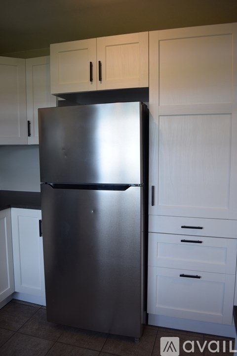 A stainless steel refrigerator in a kitchen with white cabinets.