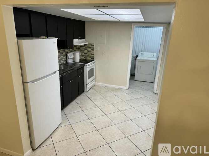 A kitchen with a white refrigerator, black cabinets, and a white dishwasher.