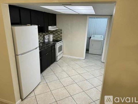 A kitchen with a white refrigerator, black cabinets, and a white dishwasher.