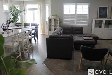 A living room with a grey couch and a dining table with chairs.