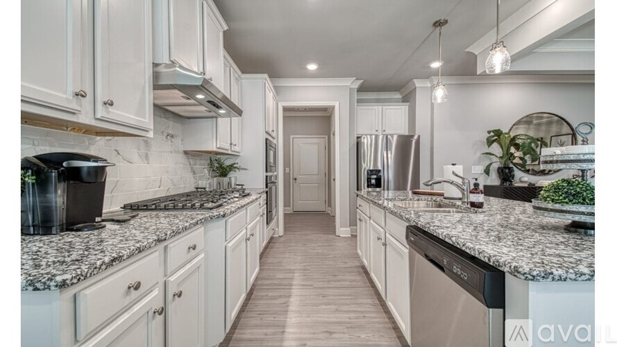 A kitchen with white cabinets and a marble countertop.