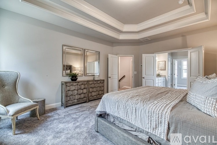 A bedroom with a large bed, a chair, and a dresser with a mirror.