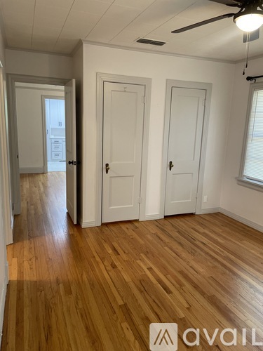 A room with wooden floors and three white doors.