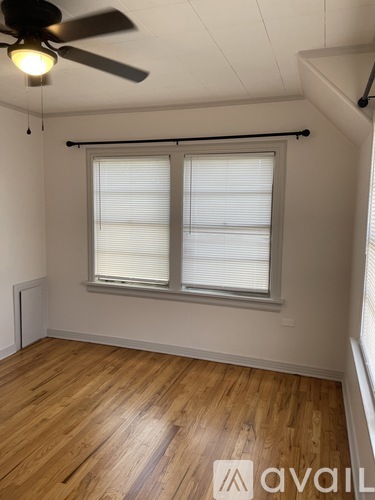 A room with a ceiling fan and a window with blinds.