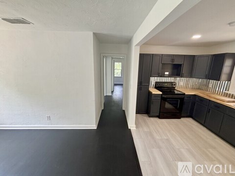 A kitchen with black cabinets and a wooden floor.