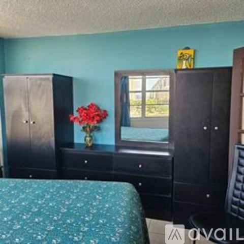 A bedroom with a bed, dresser, and a window.