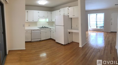 A kitchen with white cabinets and a wooden floor.