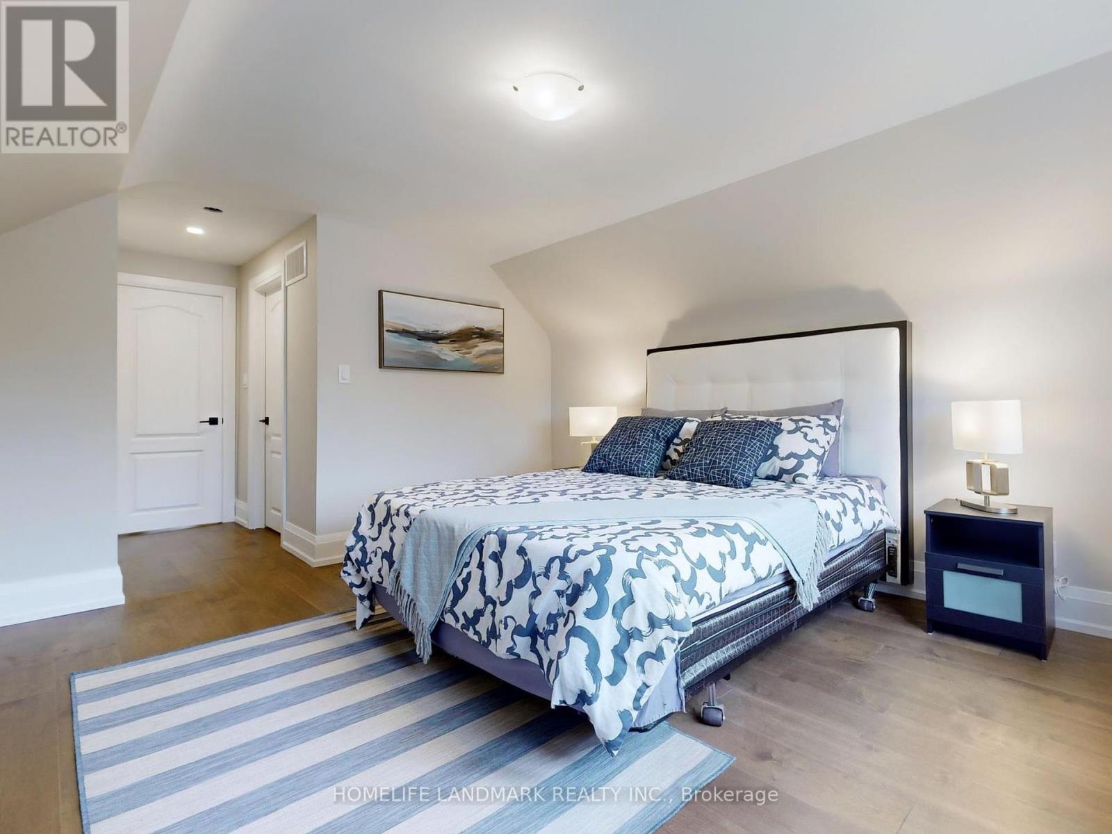 A bedroom with a large bed and a painting on the wall.