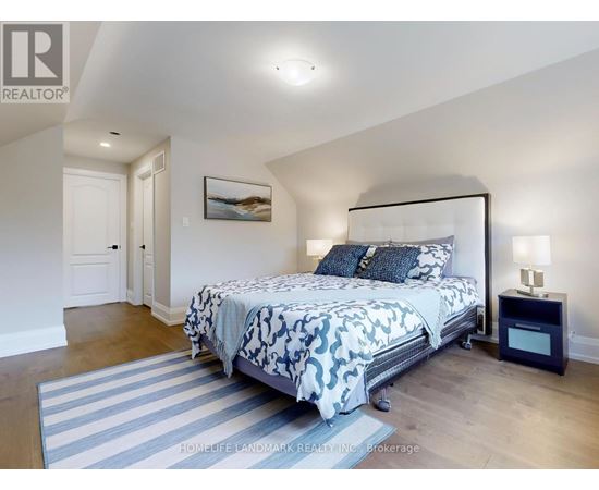 A bedroom with a large bed and a painting on the wall.