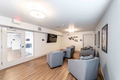 A waiting room with grey couches and a TV mounted on the wall.