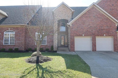 A red brick house with a tree in the front yard.