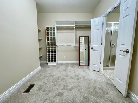A bedroom with a white door and a mirror on the wall.