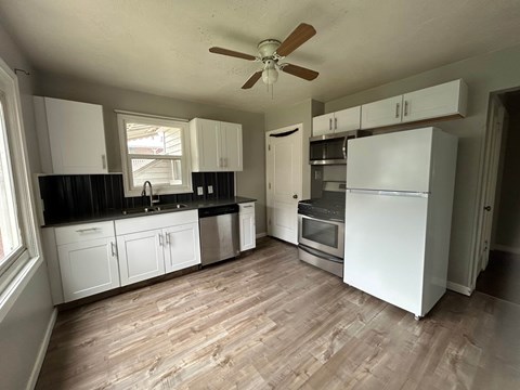 A kitchen with white cabinets and a wooden floor.