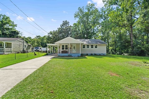 A house with a white fence and a green lawn.
