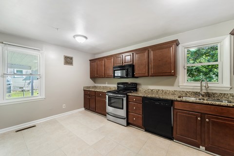 A kitchen with brown cabinets and black appliances.