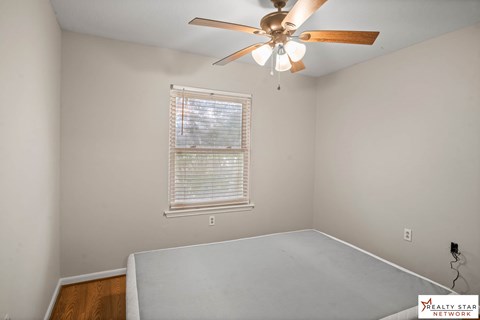 A bedroom with a ceiling fan and a window with blinds.