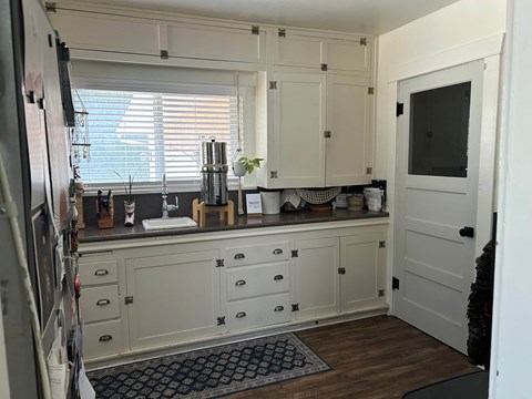 A kitchen with white cabinets and a black and white rug on the floor.
