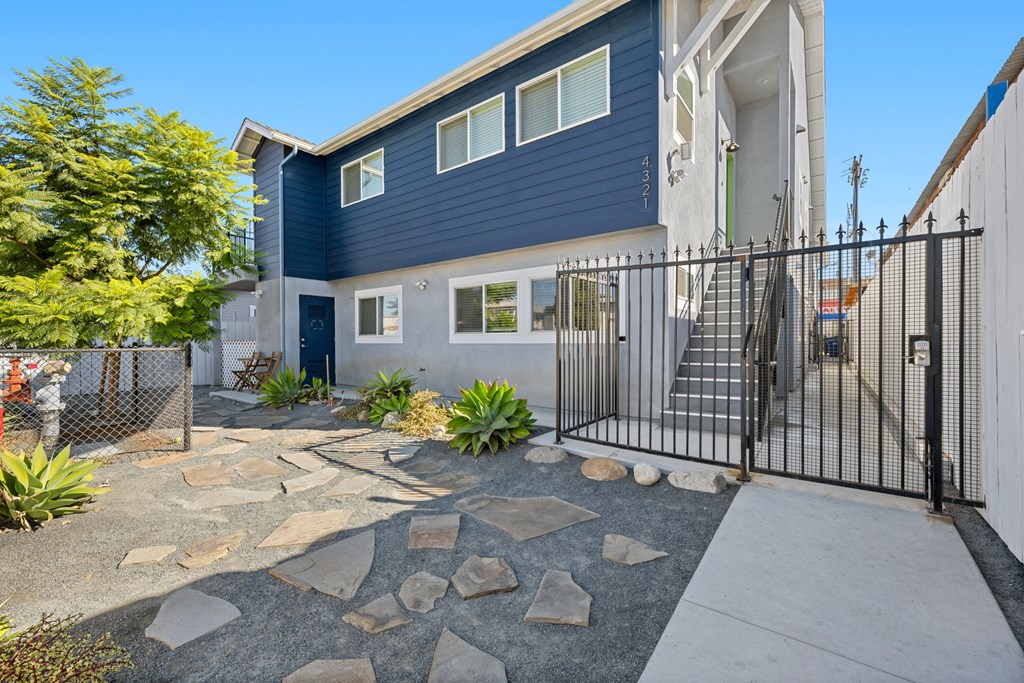 A modern house with a blue exterior and a black metal fence.