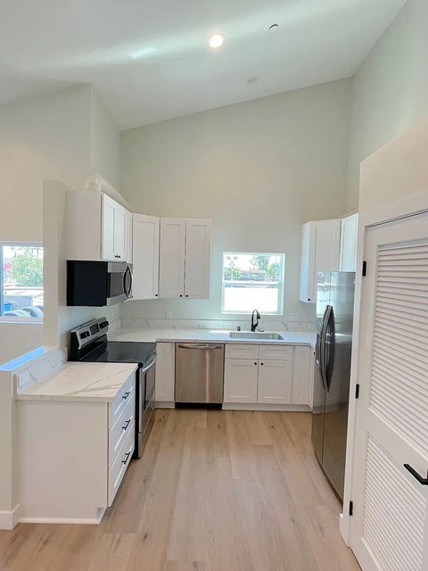 A kitchen with white cabinets and a black microwave.