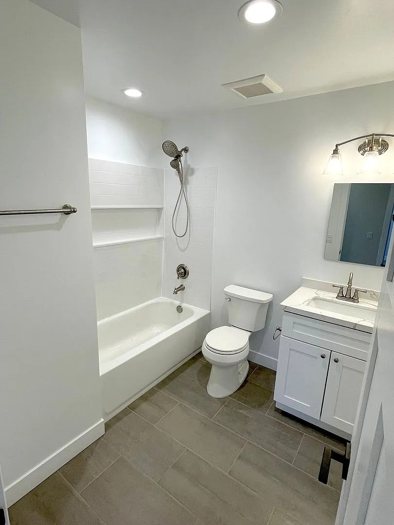 A white bathroom with a toilet, sink, and shower.