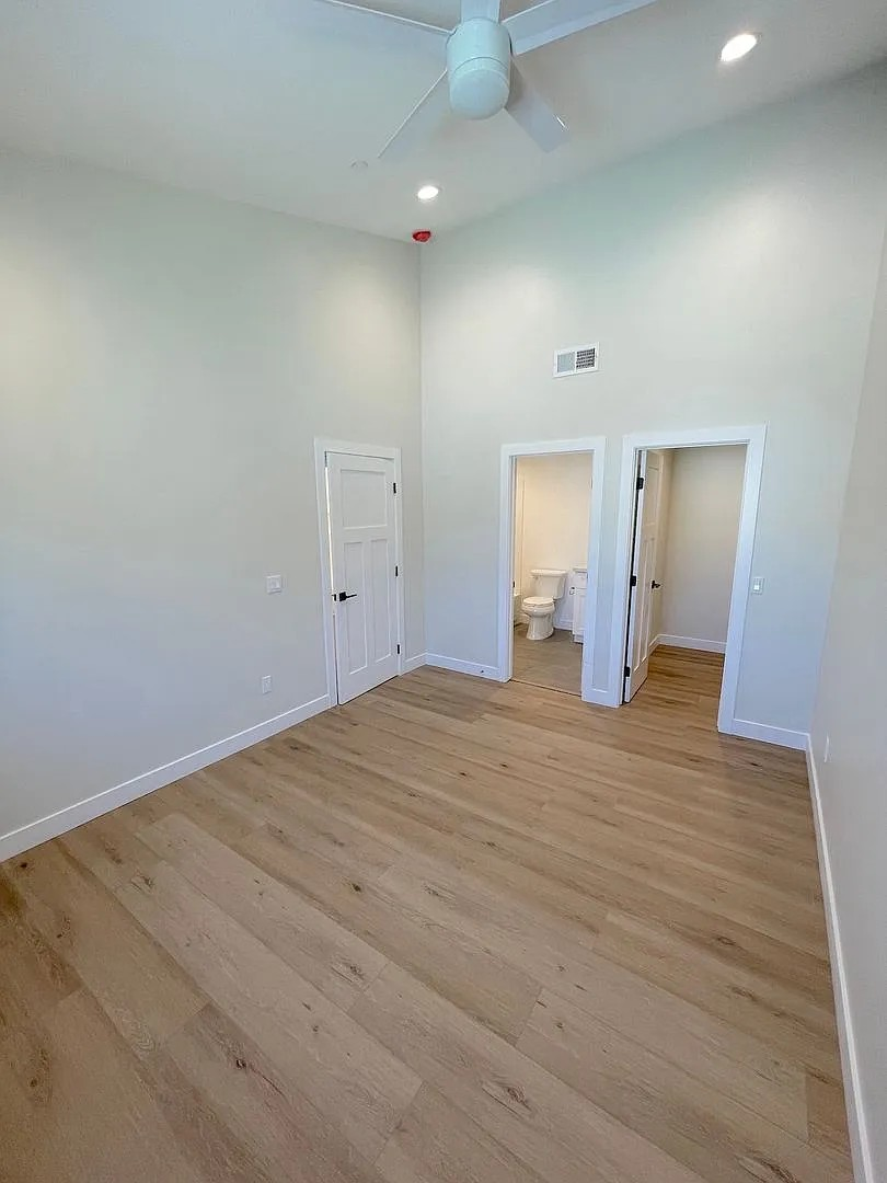 A room with a ceiling fan and wooden flooring.