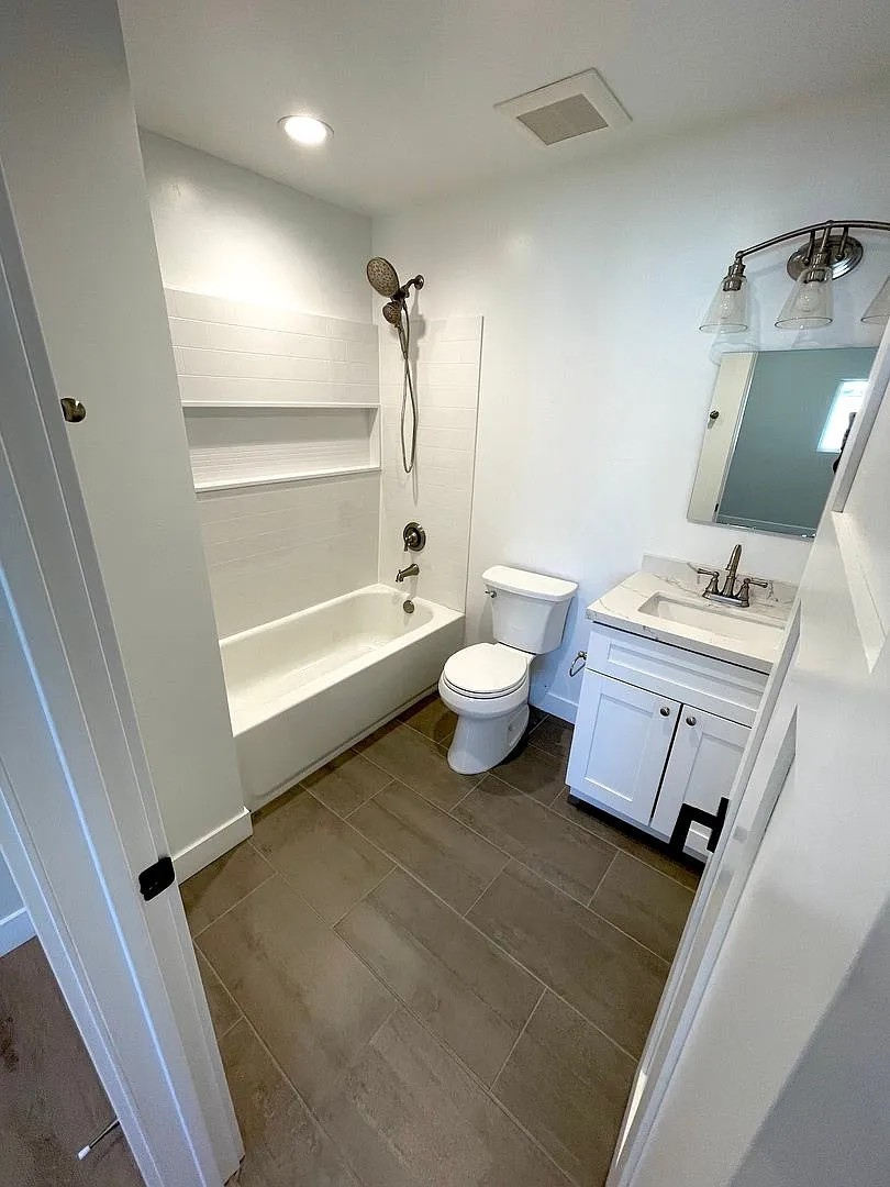 A white bathroom with a toilet, sink, and shower.