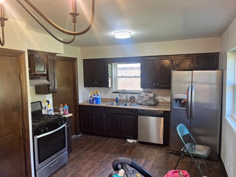 A kitchen with a stove, sink, and refrigerator.