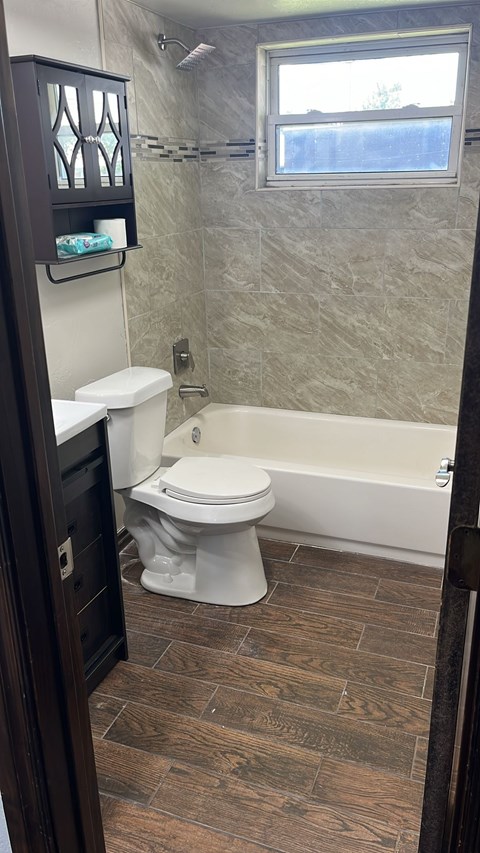 A bathroom with a toilet, a tub, and a window.