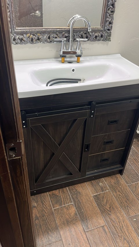 A bathroom sink with a wooden cabinet and a mirror above it.