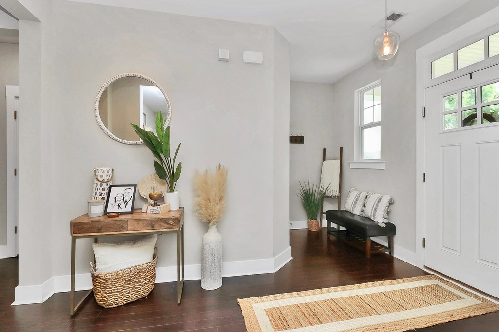 A white hallway with a round mirror and a bench.
