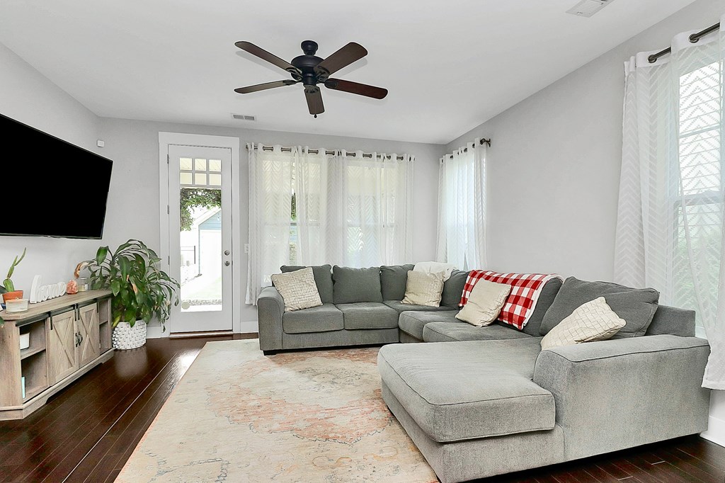 A living room with a grey couch and a ceiling fan.
