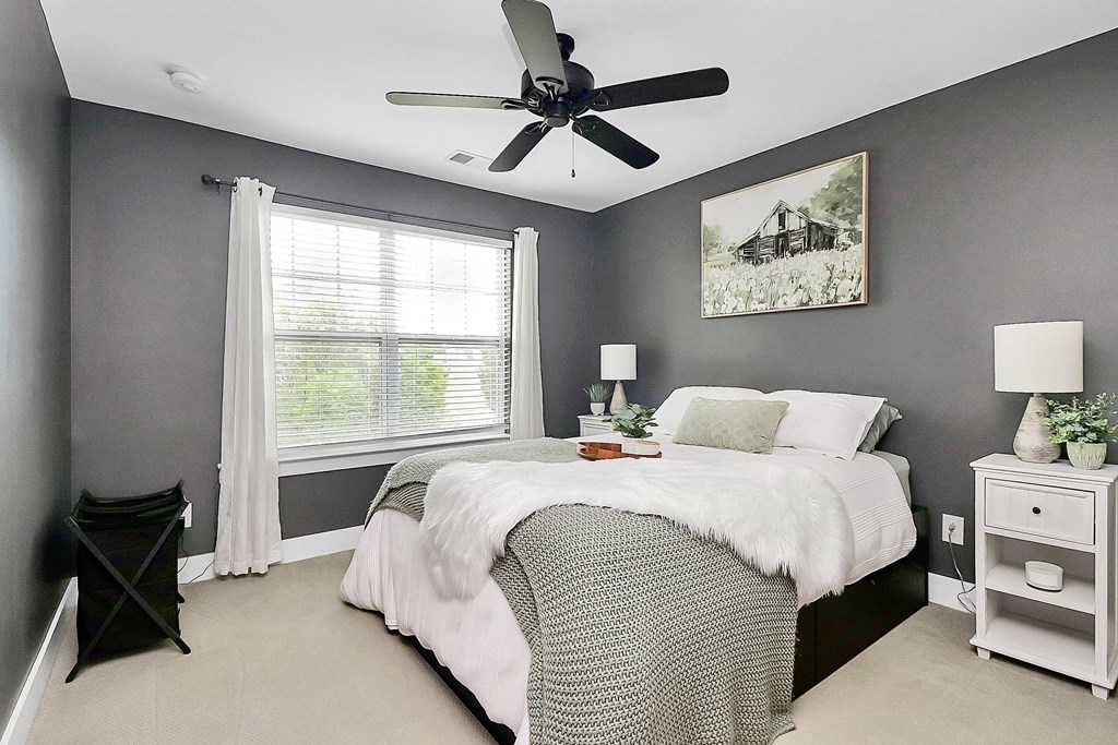 A bedroom with a bed, nightstand, and a ceiling fan.