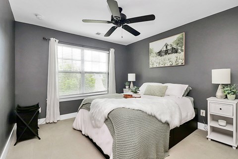A bedroom with a bed, nightstand, and a ceiling fan.